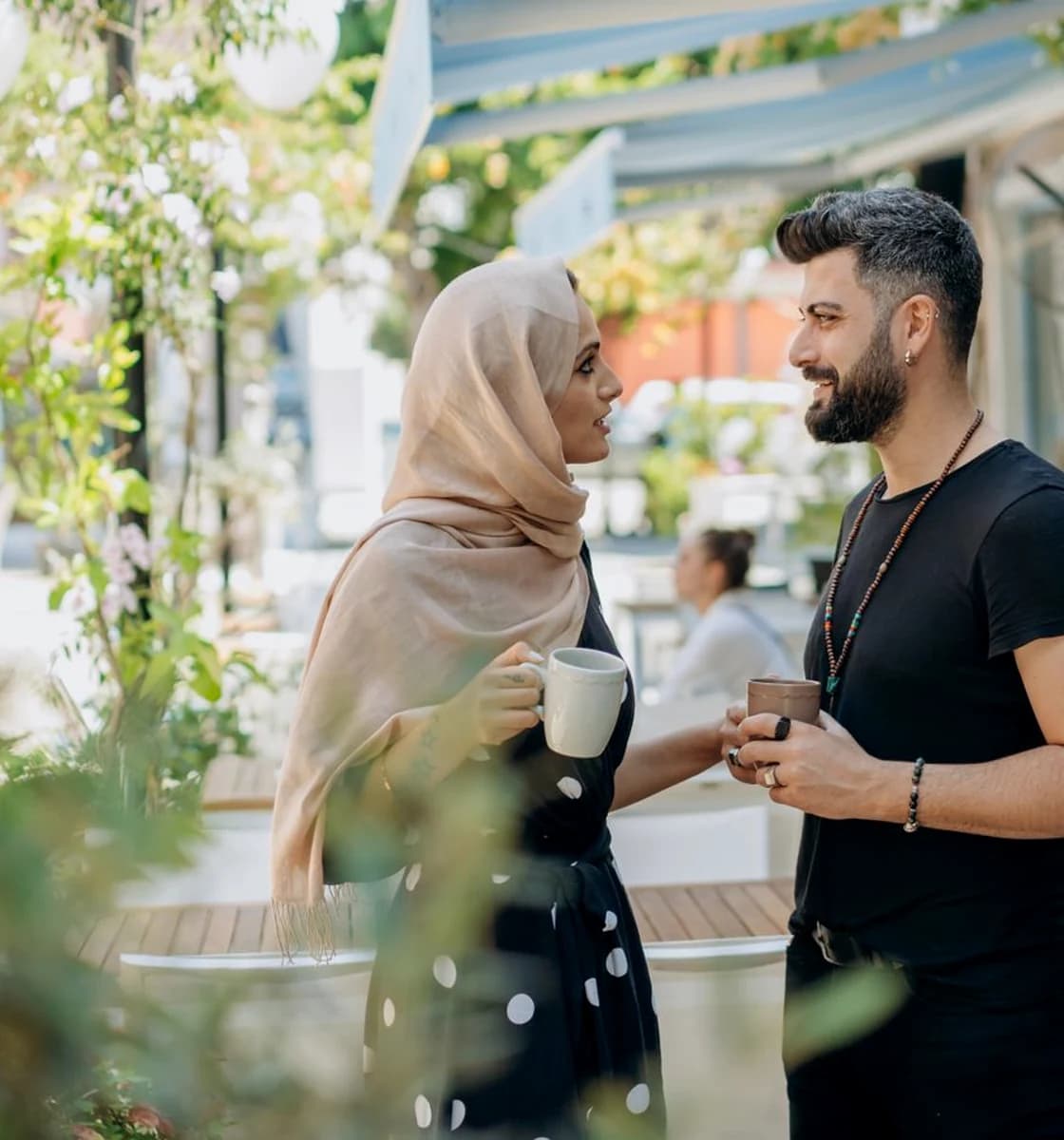 Two adults sharing a relaxed conversation at a leafy European café